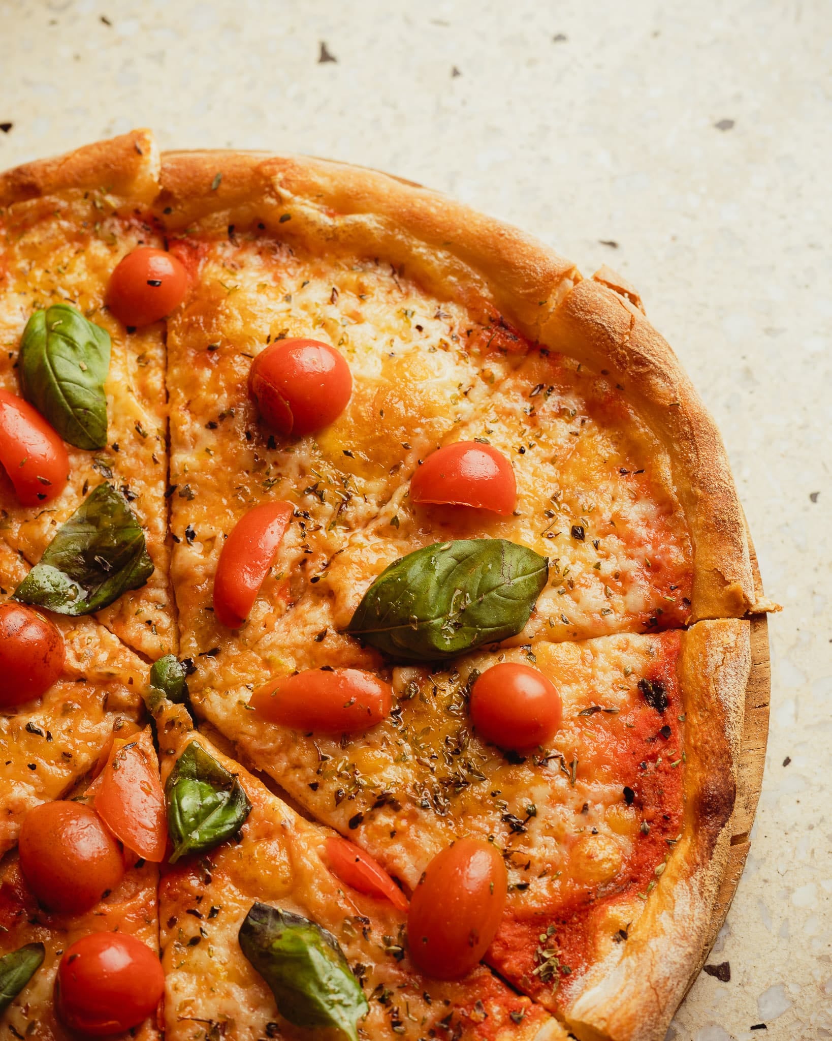 Primer plano de una pizza casera estilo margarita con tomates cherry y albahaca, parte de la selección especial de Club de Pizzas.